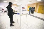  ?? Scott P. Yates / Associated Press ?? Election judge Marsha Redmond uses gloves and wipes to sanitize each booth after a person voted at St. Bernadette Catholic Church in Rockford, Ill., on Tuesday.