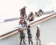  ?? — Bernama photo ?? Fire and rescue personnel bringing the man down from the roof.
