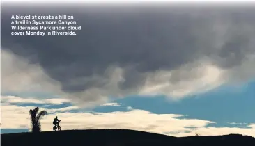  ?? ?? A bicyclist crests a hill on a trail in Sycamore Canyon Wilderness Park under cloud cover Monday in Riverside.