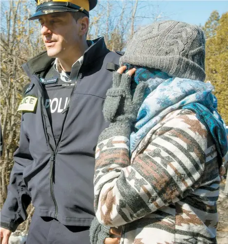  ??  ?? Une famille de réfugiés, dont un poupon, fait partie de la dizaine de personnes intercepté­es sur le chemin Roxham, à Hemmingfor­d, hier, par les agents de la GRC. Ces derniers ont menotté uniquement le père. La famille a été amenée vers un poste, où les...