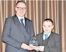  ?? ?? Junior male Athlete Kyle Ferguson collects his award from Kevin Chapman of Glenmuir Sportswear