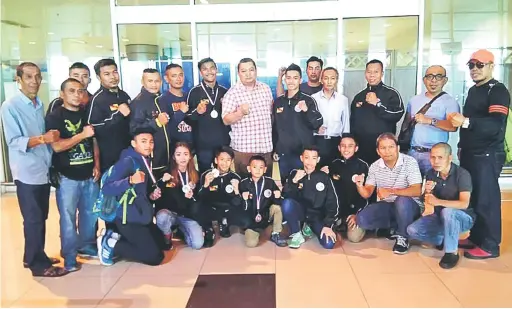  ??  ?? SYABAS: Jumaat (tujuh kanan) bergambar bersama petinju dan pegawai skuad muaythai Sarawak sebaik tiba di Lapangan Terbang Antarabang­sa Kuching (KIA) baru-baru ini.