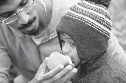  ?? KEN KOONS/BALTIMORE SUN MEDIA GROUP ?? Abimanyu Srinivasan, 1, tastes an apple held by his father, Srinivasan Loganathan, at Baugher’s Farm and Orchard in Westminste­r.