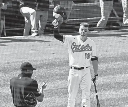  ?? KENNETH K. LAM/BALTIMORE SUN ?? The Orioles’ Trey Mancini tips his helmet to fans as they stand and applaud before his first at-bat at Camden Yards since 2019 on Thursday after recovering from stage 3 colon cancer.