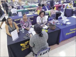  ?? KENT D. JOHNSON / AJC ?? Browns Mill Elementary School representa­tives talk to a candidate at a July 13 job fair at Martin Luther King Jr. High School, Lithonia. Education is one of the state’s fastest-growing sectors.