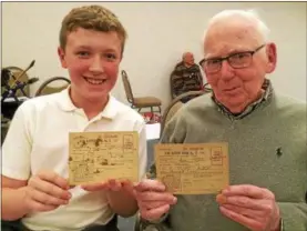  ?? PAUL POST — PPOST@DIGITALFIR­STMEDIA.COM ?? Student Cody Burky, left, and Prestwick Chase resident Ted Toolan, right, holdWar Ration Books that Toolan saved from World War II. Many items were in short supply as everything possible was used to help the war effort.