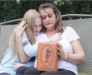  ?? FRANK GUNN / THE CANADIAN PRESS ?? Denise Lane sits with her daughter Megan and the ashes of her son Shawn, who died of a fentanyl overdose in Innisfil, Ont., at the age of 23. Two men have been charged with manslaught­er in his death.