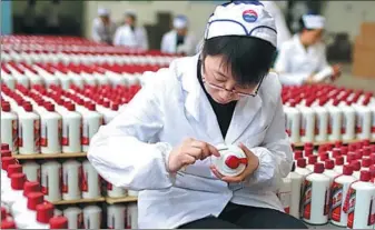  ?? PROVIDED TO CHINA DAILY ?? An employee of Kweichow Moutai Co Ltd puts labels onto bottles of the Chinese liquor.