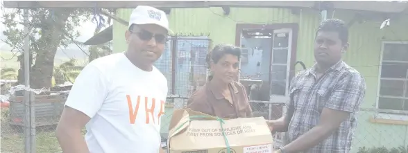  ?? Photo: Jay Dayal. ?? President of VHP, Jay Dayal (left ), distribute­s relief packs at Vaqia, Ba.