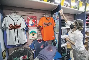  ?? Mel Melcon Los Angeles Times ?? DANIELA PRIETO, an employee at Deportes Prieto in Boyle Heights, disinfects the store Wednesday, a day after the city allowed retail businesses to allow customers inside their stores with safety protocols.