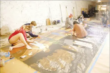  ?? LYNN KUTTER ENTERPRISE-LEADER ?? A mural being painted by members of Farmington Junior High Art Club has the theme, “We Are The Difference.” Here, students are painting on the floor of Octavio Logo’s studio in Fayettevil­le. Logo is an internatio­nally known mural artist.