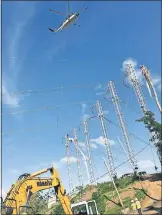  ?? [OKLAHOMAN ARCHIVES] ?? A helicopter lifts a power line for Cobra Acquisitio­ns crew members as they work to restore power to Puerto Rico in 2018. The company has been pulling its equipment it used to help repair the island's grid back to the mainland in recent months.