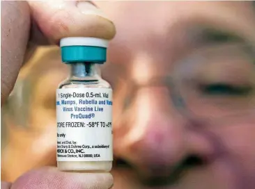  ?? [AP FILE PHOTO] ?? A pediatrici­an holds a dose of the measles-mumps-rubella vaccine in 2015 at his practice in California.