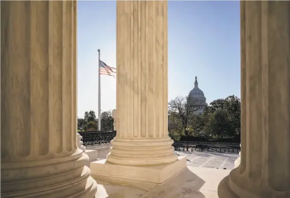  ?? J. Scott Applewhite / Associated Press ?? The Capitol peeks through columns on the U. S. Supreme Court building, where President Trump’s campaign is seeking to block the counting of absentee ballots.