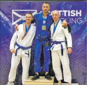  ??  ?? Oban BJJ’s Mateusz Grabiec, centre, picked up two gold medals at the West of Scotland winter cup tournament held at Ravenscrai­g recently.