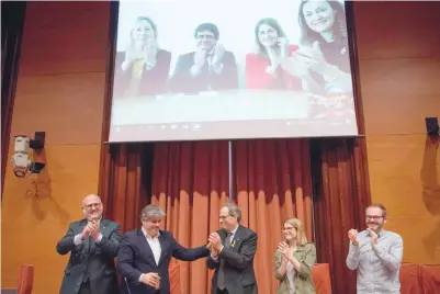  ??  ?? Junts per Catalonia (Together for Catalonia) MPS Eduard Pujol, Albert Batet, Quim Torra, Elsa Artadi and Josep Costa applaud as former Catalan president Carles Puigdemont (top 2ndl) appears on a screen during a party meeting at the parliament of...