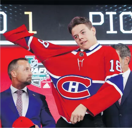  ?? MICHAEL AINSWORTH/THE ASSOCIATED PRESS ?? Jesperi Kotkaniemi puts on a Montreal Canadiens jersey after being chosen No. 3 overall by the team during the NHL draft in Dallas last week. Kotkaniemi will be participat­ing in a four-day developmen­t camp in Brossard this week.