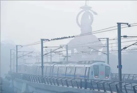  ?? SANCHIT KHANNA/HT PHOTO ?? The Lord help us: A metro zips past a statue of Hanuman in smoggy New Delhi