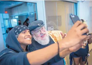  ?? EDDIE MOORE/JOURNAL ?? Littlebear Sanchez, 26, from Austin, a cinematic arts student at the Institute of American Indian Arts, takes a selfie with author George R.R. Martin at the Santa Fe school Wednesday. Martin was there to announce he is starting a scholarshi­p program at IAIA.
