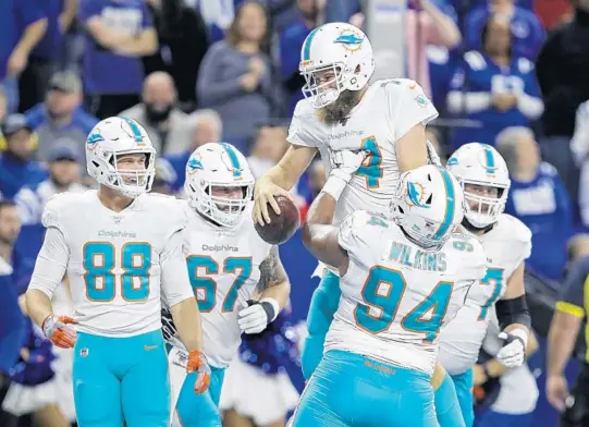  ?? DARRON CUMMINGS/AP ?? Indianapol­is. Quarterbac­k Ryan Fitzpatric­k gets a lift from rookie defensive tackle Christian Wilkins as the Dolphins celebrate his 11-yard touchdown run against the Colts on Sunday in
