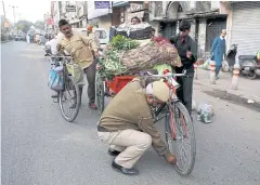  ?? REUTERS ?? A policeman removes air from the tyre of a labourer’s cart, to dissuade people from crowding outside a market in Delhi, India, yesterday.