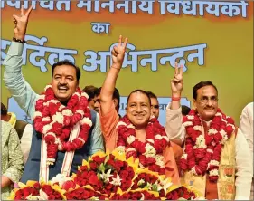  ?? IANS ?? BJP’s Uttar Pradesh Chief Minister designate Yogi Adityanath (C) with Deputy Chief Ministers designate Keshav Prasad Maurya (L) and Dinesh Sharma (R) wave during a press conference in Lucknow on Saturday.