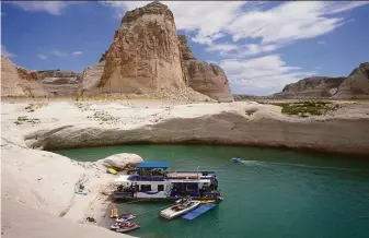  ?? Rick Bowmer / Associated Press ?? A houseboat rests in a cove on Lake Powell near Page, Ariz., in July. Drought across the West drained reservoirs this year, cutting hydropower and stressing the region’s energy grids.