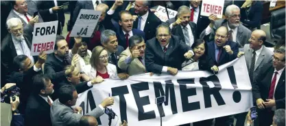  ??  ?? BRASILIA: Deputies from opposition parties carry a banner that reads in Portuguese ‘Temer Out!’ during a key vote by the lower chamber of Brazil’s Congress on whether to suspend Brazil’s President Michel Temer and put him on trial over an alleged...