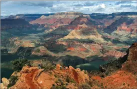  ?? Associated Press photo ?? This Feb. 22, 2005 file photo shows the North Rim of the Grand Canyon, background, as tourists hike along the South Rim in Grand Canyon, Ariz. Lower snowfall in recent years at the Grand Canyon’s North Rim is prompting tourism officials to expand the visiting season for tourists. The North Rim typically closes from mid-October to mid-May because of snow. But the one road that goes into the lesser visited part of the Grand Canyon now often doesn’t have snow by Dec. 1. Tourism officials say climate change could work in their favour to bring in more visitors and revenue to the region.