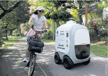  ??  ?? A cyclist passes as Carmello, an autonomous grocery delivery robot, carries out a delivery in Singapore, on April 6.