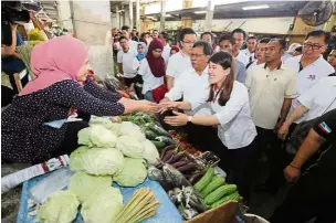  ??  ?? Nice to meet you: Shafie and Wong visiting traders and shoppers during a walkabout at Sandakan Central Market.