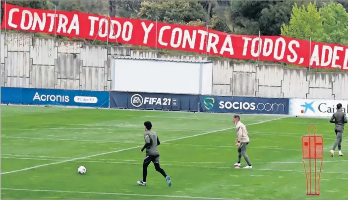  ??  ?? Los jugadores del Atlético se entrenan en el Cerro del Espino con la pancarta que pusieron los aficionado­s (“Contra todo y contra todos, adelante campeón”) en una valla.