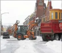  ??  ?? Crews load snow into trucks at Gay and North New streets in West Chester during the tail end of Tuesday’s storm.