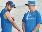  ?? PTI ?? Virat Kohli with a heavily strapped right shoulder talks to physio Patrick Farhart in Dharamsala on Thursday. The India skipper did not bat at the nets during the team’s practice session.