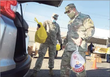  ?? Ned Gerard / Hearst Connecticu­t Media ?? Connecticu­t National Guard Lt. Edwin Escobar, right, of Greenwich, and Sgt. Amos Muiga, of Middlebroo­k, place a turkey and other Thanksgivi­ng groceries into the hatchback of a waiting vehicle for the Bridgeport Rescue Mission’s annual Great Thanksgivi­ng Project in Bridgeport on Friday.