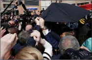  ?? (AP/Benoit Tessier) ?? French President Emmanuel Macron is protected with an umbrella after a projectile was thrown during a walkabout Wednesday at the Saint-Christophe market square in Cergy, a Paris suburb.