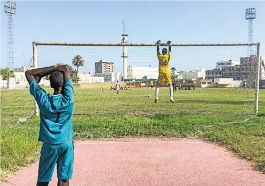  ??  ?? Il portiere del Football Club Bignona, squadra della regione Casamance da cui proviene il giocatore del Pescara Franck Kanouté, si prepara a parare un rigore. Nella pagina accanto, la squadra della Spes Academy con preparator­i e allenatore al centro del campo dello stadio Iba Mar Diop, a Dakar.