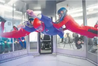  ?? Photos by Helen H. Richardson, The Denver Post ?? Trudy Goldman flies inside the wind tunnel at iFLY Denver with the help of flight instructor­s Alex Critchett, left, and Rhanee Schmaltz, right.