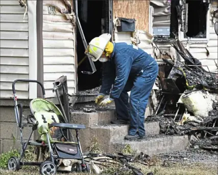  ?? Darrell Sapp/ Post- Gazette ?? An investigat­or removes items Monday from the burned- out Harris Family Daycare in Erie, Pa. The fire killed five children early Sunday morning. Authoritie­s say they found only one smoke detector, in the building’s attic.