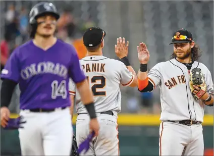  ?? Getty Images/tns ?? Brandon Crawford and Joe Panik of the San Francisco Giants celebrate a 19-2 win over the Colorado Rockies as Tony Wolters of the Colorado Rockies walks off the field after making the final out during game one of a doublehead­er at Coors Field on Monday in Denver, Colo.
