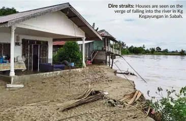  ??  ?? Dire straits: Houses are seen on the verge of falling into the river in Kg Kegayungan in Sabah.