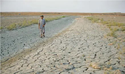  ?? ANMAR KHALIL/AP ?? A fisherman walks across a dry patch of marshes Sept. 2 in southern Iraq. The area has suffered from drought and rising salinity levels.