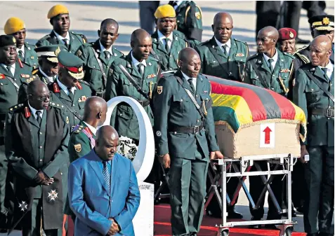  ??  ?? A ‘this way up’ sticker adorns Mugabe’s coffin as his widow Grace, left, arrives at Robert Mugabe Internatio­nal Airport, Harare