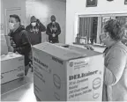  ?? PHOTOS BY RYAN GARZA/DETROIT FREE PRESS ?? Chatman, background left, and Moore, background, talk with the Baldwin Center Director of Community Engagement Heather Duenas, right, after dropping off three boxes of food.