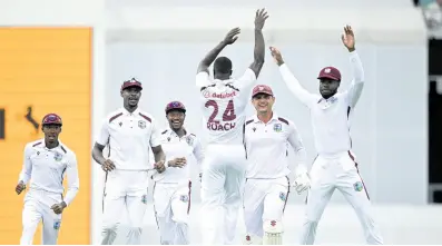  ?? AP ?? West Indies’ Kemar Roach (centre) celebrates with teammates after taking the wicket of Australia’s Cameron Green on the second day of the second Test in Brisbane yesterday.