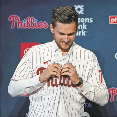  ?? MATT SLOCUM/AP ?? Newly acquired Phillies shortstop Trea Turner puts on a jersey during his introducti­on in Philadelph­ia on Dec. 8.