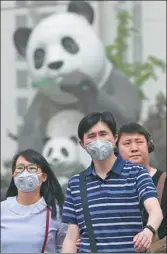  ?? WANG ZHUANGFEI AND FENG YONGBIN / CHINA DAILY ?? Left: Many people in the Wangjing area of Beijing don masks on Thursday, following health officials’ recommenda­tions. Right: A visitor takes a photo of the Forbidden City through the haze of a sandstorm.