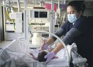  ??  ?? NURSE MARIA BROWN cares for Jade last month in the neonatal intensive care unit at Loma Linda University Children’s Hospital. Jade tested negative for COVID- 19 at birth.