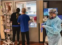  ?? ANDREW SELSKY/AP ?? Visitors peer into the ICU room of a COVID-19 patient at Salem Hospital in Salem, Oregon, on Aug. 20 as a nurse dons full protective
gear before going into the room of another patient.