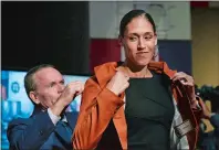  ?? JESSICA HILL/AP PHOTO ?? Naismith Basketball Hall of Fame inductee Rebecca Lobo, right, the former UConn All-American, adjusts her jacket as it is presented to her by Hall of Fame president and CEO John Doleva during a news conference Thursday in Springfiel­d.